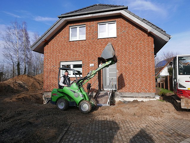 Bagger mit erhobener Schaufel als triumphale Geste der perfekten Zusammenarbeit